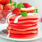Stapel von roten Samtpfannkuchen mit Joghurt und Erdbeere - nicht nur lecker, sie sehen auch toll aus