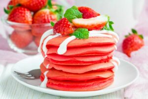 Stapel von roten Samtpfannkuchen mit Joghurt und Erdbeere - nicht nur lecker, sie sehen auch toll aus